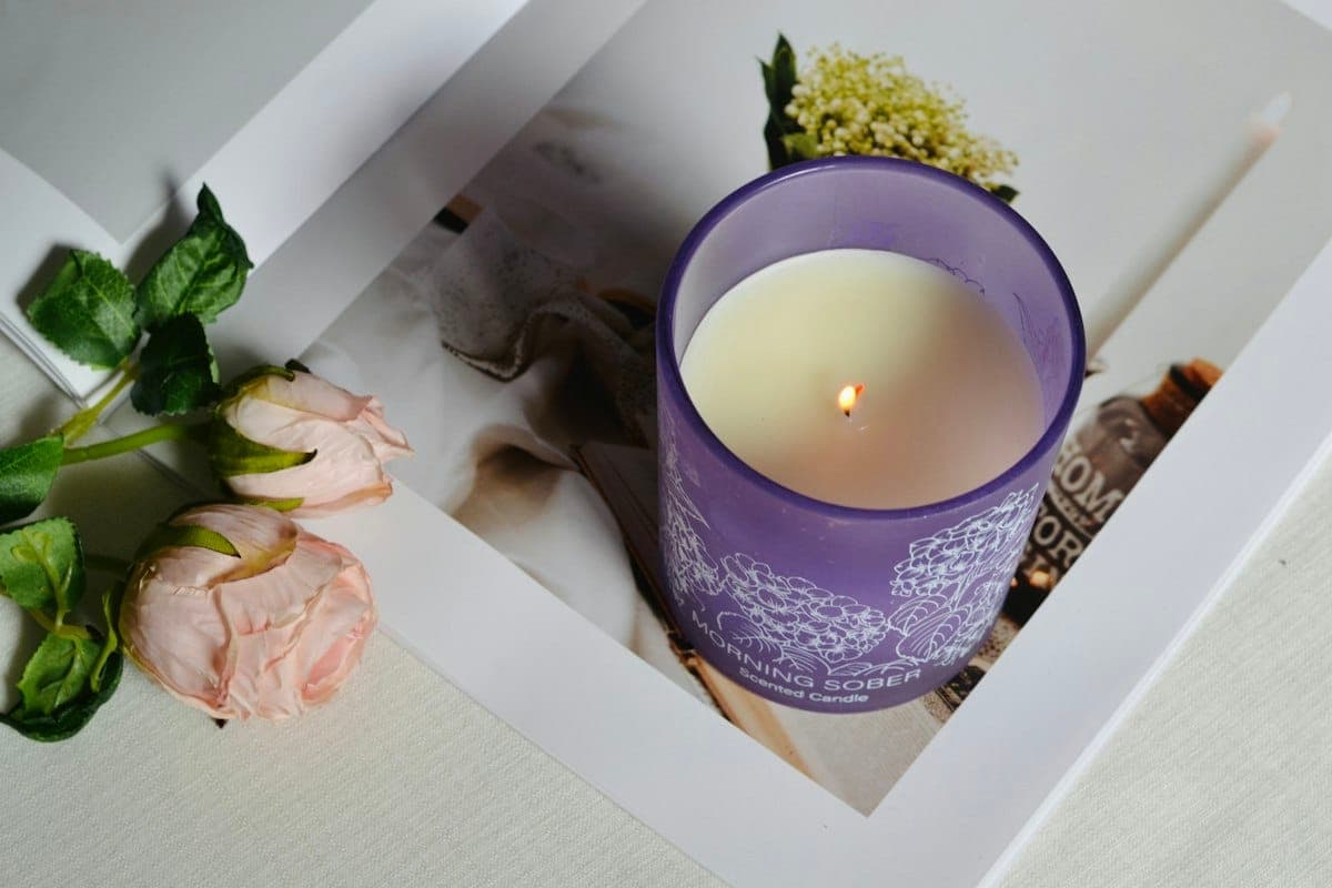 A lit candle and roses in memory — on a real page, a portrait supplied by the family.